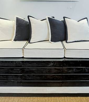 Respiradouro transformado em sofá. Tapado com placas de deck pintadas de preto e com almofadas por cima 